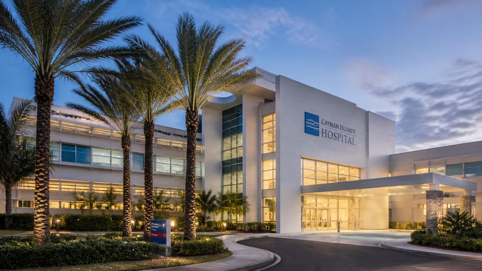 Modern Caribbean hospital exterior at dusk with palms